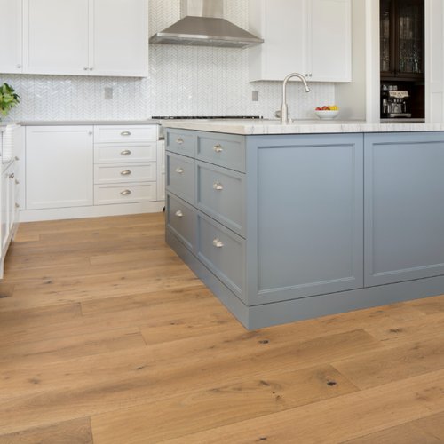Blue kitchen island and white cabinets in a kitchen with warm hardwood flooring